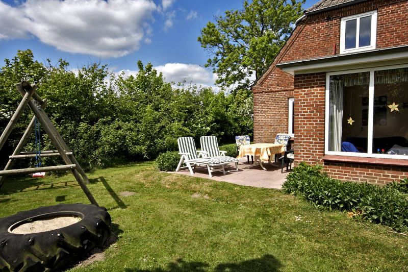 Terrasse mit Liegestühlen, Garten mit Klettergerüst, Schaukel und Sandkasten